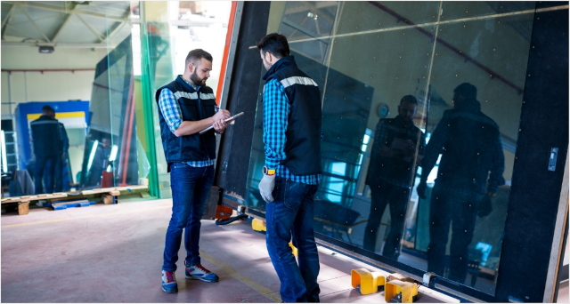 2 men reviewing glass panel